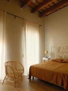 a bedroom with a bed and a chair and a window at Casa Reina Cabanyal in Valencia