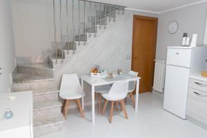 a white kitchen with a table and white chairs at A casa dello scalpellino in Contursi