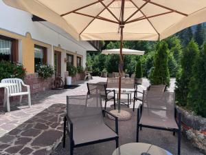 a patio with tables and chairs with an umbrella at Albergo Scoiattolo Dolomites Experience in Falcade