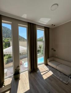 ein Wohnzimmer mit Sofa und großen Fenstern in der Unterkunft The pause in Delvinë