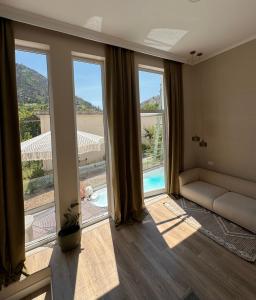 ein Wohnzimmer mit großen Fenstern und einem Sofa in der Unterkunft The pause in Delvinë