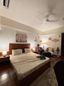 a man sitting on a bed in a bedroom at Bs BnB Luxury Studio Apartment in Dehradun