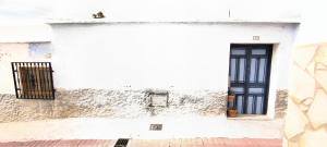a white building with a black door and a window at Casa Diafa in Órgiva +5 photos
