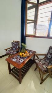a table with fruit on it next to two chairs at Fish House in Nungwi