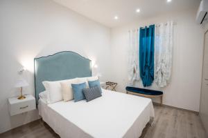 a bedroom with a large white bed and blue curtains at Santa Rosa Relais in Conca dei Marini