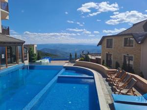 a swimming pool with chairs and a view of the mountains at Milmari L29 in Kopaonik