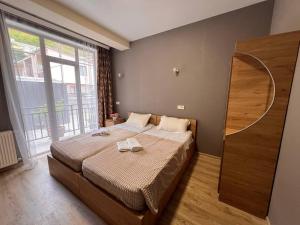 a bedroom with a bed and a large window at Memory- borjomi in Borjomi