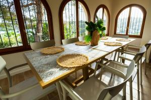 a dining room with a table with chairs and windows at Villa Paula in Benissa