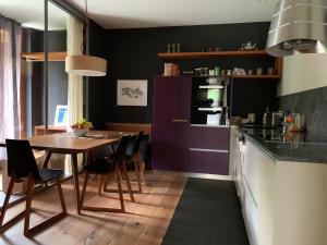 a kitchen with a wooden table and purple cabinets at Chalet Park Apartment mit Sauna Hamam in Diemtigen +32 photos