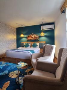 a bedroom with a bed and two chairs and a couch at Modern Palace Hotel in Al Fayşalīyah