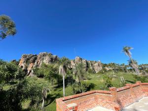 a view of a mountain with palm trees and a brick wall at Villa Virgen De La Gracia in Tobatí +1 photo