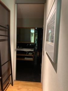a hallway with a bathroom with a sink and a mirror at Chalet Park Apartment mit Sauna Hamam in Diemtigen
