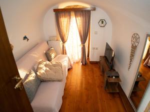 a living room with a white couch and a television at Elata Stone Retreat Traditional Village House in Chios