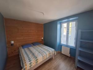 a bedroom with a bed with blue walls and a window at Logis du fresne in Saint-Lormel