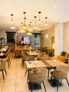 a restaurant with tables and chairs and a flat screen tv at Hôtel Abalone - Centre Gare in Nîmes