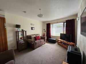 a living room with a chair and a television at 8 Jib Park, Orkney Islands in Finstown