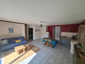 a living room with a blue couch and a kitchen at Logis du fresne in Saint-Lormel