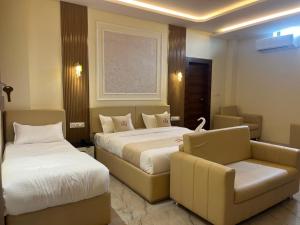 a hotel room with two beds and a couch at Hotel Shanvi Inn in Jabalpur