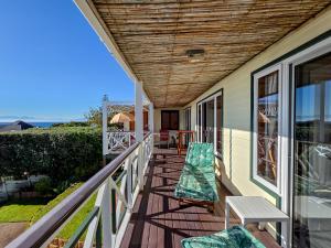a porch with two chairs and a table on it at Eindelik in Simonʼs Town