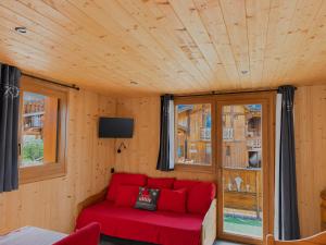 a living room with a red couch and windows at Le Génépi in La Plagne Tarentaise