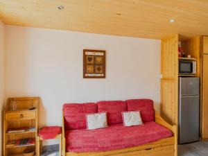 a red couch in a room with a refrigerator at Le Génépi in La Plagne Tarentaise +9 photos