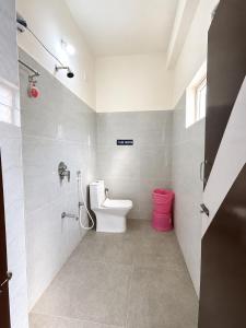 a bathroom with a toilet and a pink trash can at MGR RESIDENCY in Srikalahasti