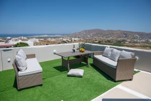 a patio with a table and chairs and grass at Aurora Horizon Naxos in Glinádhon