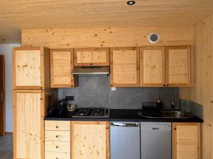 a kitchen with wooden cabinets and a stove at L'edelweiss in La Plagne Tarentaise