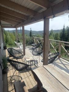 a deck with chairs and a wooden table and benches at Järvsöbranten 7 med 10 sovplatser och vedeldad badtunna, 400 m från lift in Järvsö