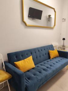 a blue couch with yellow pillows in a living room at Ancha 4 en pleno centro in Sanlúcar de Barrameda