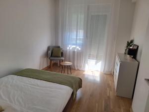 a bedroom with a bed and a chair and a window at Olea relax apartman in Brčko