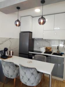 a kitchen with white cabinets and a white table and chairs at Olea relax apartman in Brčko +11 photos