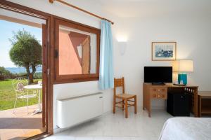 ein Zimmer mit einem Bett, einem Schreibtisch und einem Fenster in der Unterkunft Hotel Valdiola in Porto Cervo