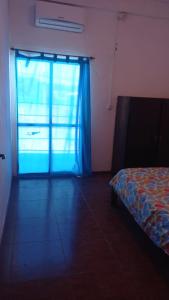a room with a bed and a window with a blue curtain at Casa Dept Alquila dia in Oro Verde