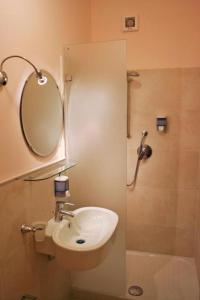 a bathroom with a sink and a mirror and a shower at Ostello City In Hostel B&B in Catania