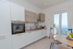 a kitchen with white cabinets and a table and a window at Santa Rosa Relais in Conca dei Marini