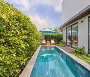 an infinity pool with chairs and an umbrella next to a house at Vip villa in Phú Quốc