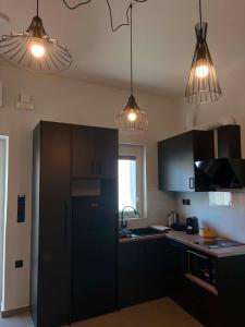 a kitchen with black cabinets and two pendant lights at Alegria Suite in Ermoupoli
