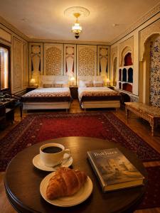 a bedroom with two beds and a coffee table with a croissant at Chorminor 1 min to Bukhara Old Town GET EARLY CHECK IN AND LATE CHECK OUT in Bukhara