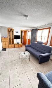 a living room with a blue couch and a table at Chalet Adler Bettmeralp 2 Schlafzimmer in Bettmeralp
