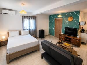 a bedroom with a bed and a tv and a couch at Le Cocon de Tahiti Plage in Sada