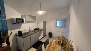 a small kitchen with a sink and a microwave at Le Cocon de Tahiti Plage in Sada