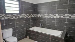 a bathroom with a bath tub and a toilet at Le Cocon de Tahiti Plage in Sada +10 photos