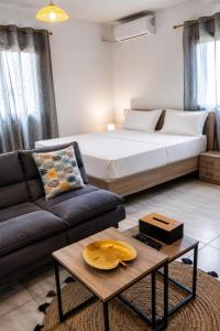 a bedroom with a bed and a couch and a table at Le Cocon de Tahiti Plage in Sada