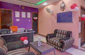 a living room with two chairs and a wall with purple at Super Hotel O Surya Inn in Varanasi +24 photos