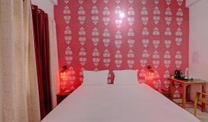 a bedroom with a white bed and a red wall at Super Hotel O Surya Inn in Varanasi
