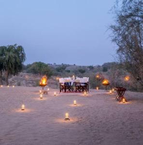 a table and chairs with candles in the sand at Yatra Desert Camp & Resort in Jaisalmer +39 photos