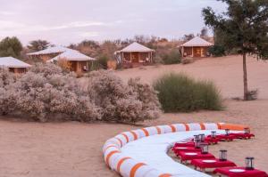 a group of red tables and chairs in front of some huts at Yatra Desert Camp & Resort in Jaisalmer
