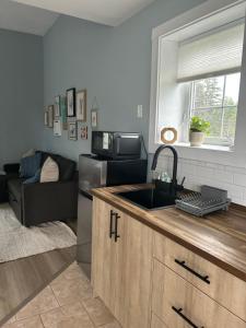a kitchen with a sink and a living room at Tides Inn Guest Suites in Halls Harbour