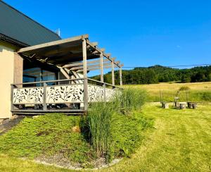 a building with a wooden deck in a field at KORBIELOVKA domek z sauną in Korbielów